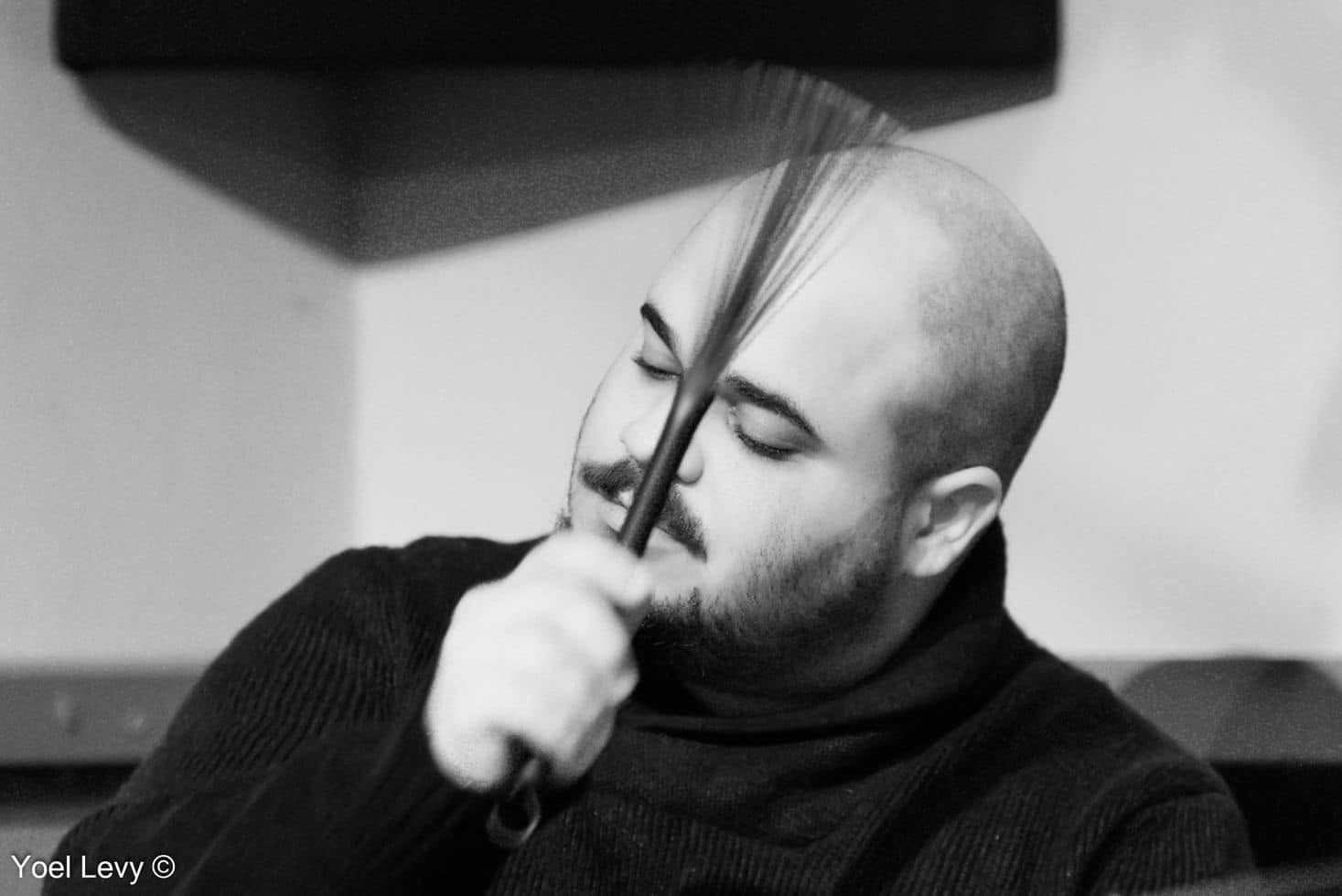 Ben Silashi with a wire brush raised to his face, eyes closed